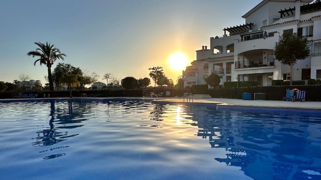 Sun rising over apartments and pool on a golf course in Murcia